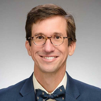 Professor Schnell in blue suit and bowtie on white background
